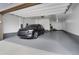 Clean, painted, and well-lit garage featuring epoxy flooring, a black SUV, and a rear service door at 8982 Delacorte St, Littleton, CO 80129