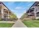 View down a sidewalk lined with modern townhomes, landscaping and green lawns under a blue sky at 8982 Delacorte St, Littleton, CO 80129