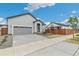 Home showcasing a spacious two-car garage, neutral siding, and a neatly landscaped front yard at 1613 Bloom St, Brighton, CO 80601