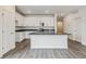 Modern kitchen with white cabinets, island with sink, stainless steel appliances, and wood floors at 1613 Bloom St, Brighton, CO 80601