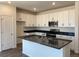 Modern kitchen featuring white cabinets, stainless steel appliances, and a dark countertop island with a sink at 1613 Bloom St, Brighton, CO 80601