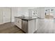 Bright kitchen with island, stainless steel dishwasher, wood floors, and open view of the living area at 1613 Bloom St, Brighton, CO 80601