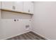 Bright laundry room with sleek gray wood-look vinyl floors, white walls and white cabinets at 1613 Bloom St, Brighton, CO 80601