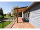 Spacious wooden deck with metal railings, ceiling fan, and view of the green, open backyard at 6668 Fairways Dr, Longmont, CO 80503