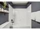 Bathroom featuring a white tiled shower-tub combo, dark gray wall, and floating shelves with decor at 6167 S Pierson St, Littleton, CO 80127