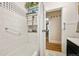 Bathroom with white tiles, towel storage, and shower, leading to dining area at 2131 Eliot St, Denver, CO 80211