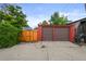 Two-car garage with brown doors, accessible via a concrete driveway and wooden gate at 2131 Eliot St, Denver, CO 80211