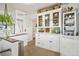 Charming, cottage-style kitchen with white cabinetry, glass display cabinet, and adjacent laundry area at 2131 Eliot St, Denver, CO 80211