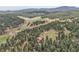 Areal shot of the residence surrounded by forest, with distant mountain views at 8851 Blue Creek Rd, Evergreen, CO 80439