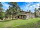 Gray two-story home with a well-kept lawn surrounded by trees, and a convenient two-car garage, offering picturesque curb appeal at 8851 Blue Creek Rd, Evergreen, CO 80439