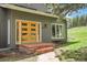 Charming home entrance with a brick porch, featuring a vibrant yellow front door and a lush green lawn at 8851 Blue Creek Rd, Evergreen, CO 80439
