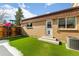 Backyard featuring artificial turf,partial snow cover, a fenced perimeter, and a brick building with a door at 12893 W Alameda Dr, Lakewood, CO 80228