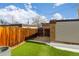 Charming backyard area with privacy fence, featuring artificial turf, concrete patio and partial snow cover at 12893 W Alameda Dr, Lakewood, CO 80228