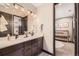 Beautiful bathroom featuring double sinks, dark cabinetry, and a view into the Bedroom at 14209 Beebalm Loop, Parker, CO 80134