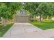 Traditional home featuring an attached garage, mature trees, green lawn, and a charming stone accent at 10535 Holyoke Dr, Parker, CO 80134