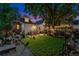 Backyard at dusk featuring well-manicured lawn, patio, garden, and seating, framed by mature trees at 3016 N Franklin St, Denver, CO 80205