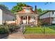 Charming red brick home with a cozy front porch, manicured lawn, and black wrought iron fence on a sunny day at 3016 N Franklin St, Denver, CO 80205