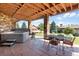 Outdoor patio with a hot tub and dining area underneath a wooden ceiling at 6170 Falcon Ln, Morrison, CO 80465