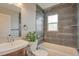 Updated bathroom featuring gray tile, a tub, modern fixtures, and a decorative plant at 6528 S Louthan St, Littleton, CO 80120