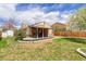 Backyard showcasing a covered patio, lush lawn, mature tree, and a privacy fence at 11420 E 1St Ave, Aurora, CO 80010