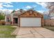Exterior of home featuring a two-car garage, stone accents, and a well-kept lawn at 11420 E 1St Ave, Aurora, CO 80010