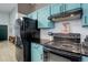 Kitchen featuring teal cabinetry and black appliances at 11420 E 1St Ave, Aurora, CO 80010