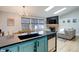 Modern kitchen featuring blue cabinets, a black countertop, and an open layout connected to the living room and dining area at 11420 E 1St Ave, Aurora, CO 80010