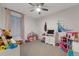 Bright bedroom featuring large window, ceiling fan, and play area at 8371 S Cody Way, Littleton, CO 80128