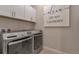 Well-lit laundry room with modern washer and dryer, along with storage cabinets at 8371 S Cody Way, Littleton, CO 80128