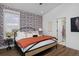 Modern bedroom features stylish wallpaper, wood floors, and a sleek metal bed frame with inviting orange blanket at 10864 Lyric St, Lone Tree, CO 80134