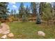 Well-maintained backyard with a lush green lawn, mature trees, and a charming picnic area for outdoor enjoyment at 26095 Columbine Trl, Kittredge, CO 80457