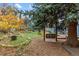 Lush backyard featuring mature trees, a swing, a fire pit area, and inviting outdoor spaces for relaxation at 26095 Columbine Trl, Kittredge, CO 80457