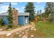 Charming home exterior featuring a stone chimney, blue siding, and a welcoming walkway leading to the front door at 26095 Columbine Trl, Kittredge, CO 80457