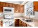 Bright kitchen featuring wood cabinets, white appliances, and a double sink at 1711 S Blackhawk Way # D, Aurora, CO 80012