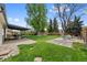 Large, landscaped backyard with a covered patio and mature trees at 4525 S Cole Ct, Morrison, CO 80465