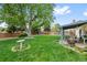 Large backyard featuring green lawn, a mature tree, and a covered patio area at 4525 S Cole Ct, Morrison, CO 80465