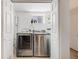 Modern laundry room with stainless steel washer and dryer and white cabinets and a window at 1765 Xenia St, Denver, CO 80220