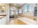 Bright bathroom with a glass-enclosed shower, soaking tub, and a view to the bedroom, creating a luxurious space at 5280 Longs Peak St, Brighton, CO 80601