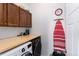 The well-lit laundry room has side-by-side washer and dryer, a folding counter, and overhead storage at 9690 E 5Th Ave, Denver, CO 80230