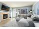 Bright living room featuring a cozy fireplace, large windows, and a comfortable gray sectional sofa and rug at 9690 E 5Th Ave, Denver, CO 80230