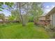 Green backyard with mature trees provides shade and privacy, extending to a deck area of the house at 2871 Humboldt Cir, Longmont, CO 80503