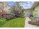 Well-maintained backyard featuring lush greenery, mature trees, and a concrete path leading to the house at 2871 Humboldt Cir, Longmont, CO 80503
