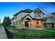Elegant two-story home with a stone facade, covered front porch, manicured lawn, and wrought iron fence at 2500 S Clayton St, Denver, CO 80210