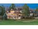Rear exterior view of a large brick home with a deck, stairs, and manicured lawn at 101 Glenmoor Ln, Cherry Hills Village, CO 80113