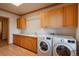 Bright laundry room with wooden cabinets, counter space, sink, and modern washer and dryer at 101 Glenmoor Ln, Cherry Hills Village, CO 80113