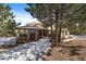 Tan two story house with a covered patio and large trees in the front yard with snow on the ground at 1366 Killington Ct, Evergreen, CO 80439