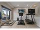 This workout area has a treadmill, stationary bike, dumbbells and a walkout to a patio at 1366 Killington Ct, Evergreen, CO 80439