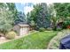 Landscaped backyard featuring a large grassy area, mature trees, shed, and rock garden beds at 20855 E Lyttle Dr, Parker, CO 80138