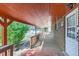 Side porch featuring a brick facade, wooden floorboards and railings with a view of the lawn and white picket fence at 1101 Dakin St, Denver, CO 80221