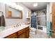 Bathroom featuring a shower-tub combo, wooden vanity with marble countertop, and updated fixtures at 1853 Burton St, Strasburg, CO 80136